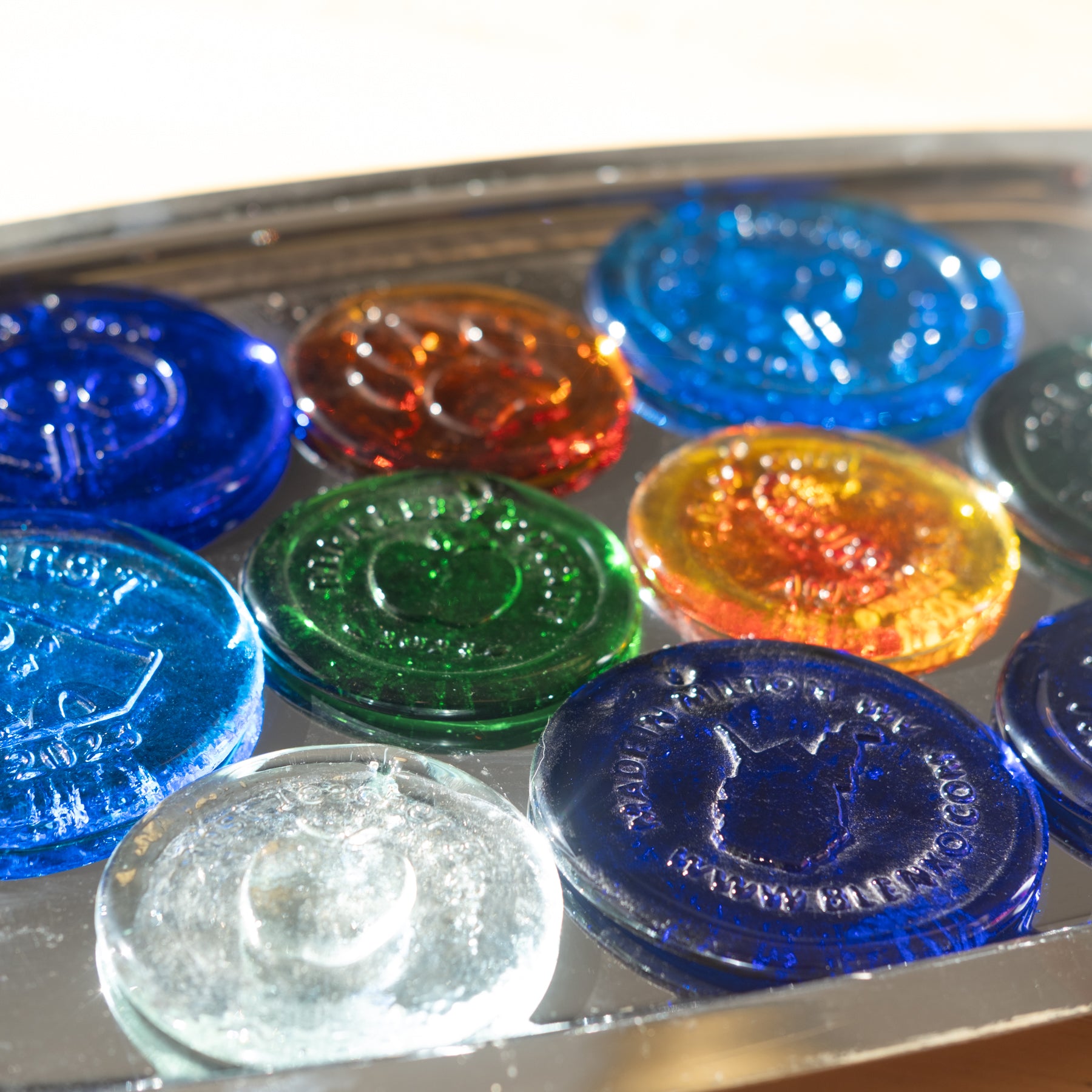 Image depicts several suncatchers in multiple colors with varying organization logos.